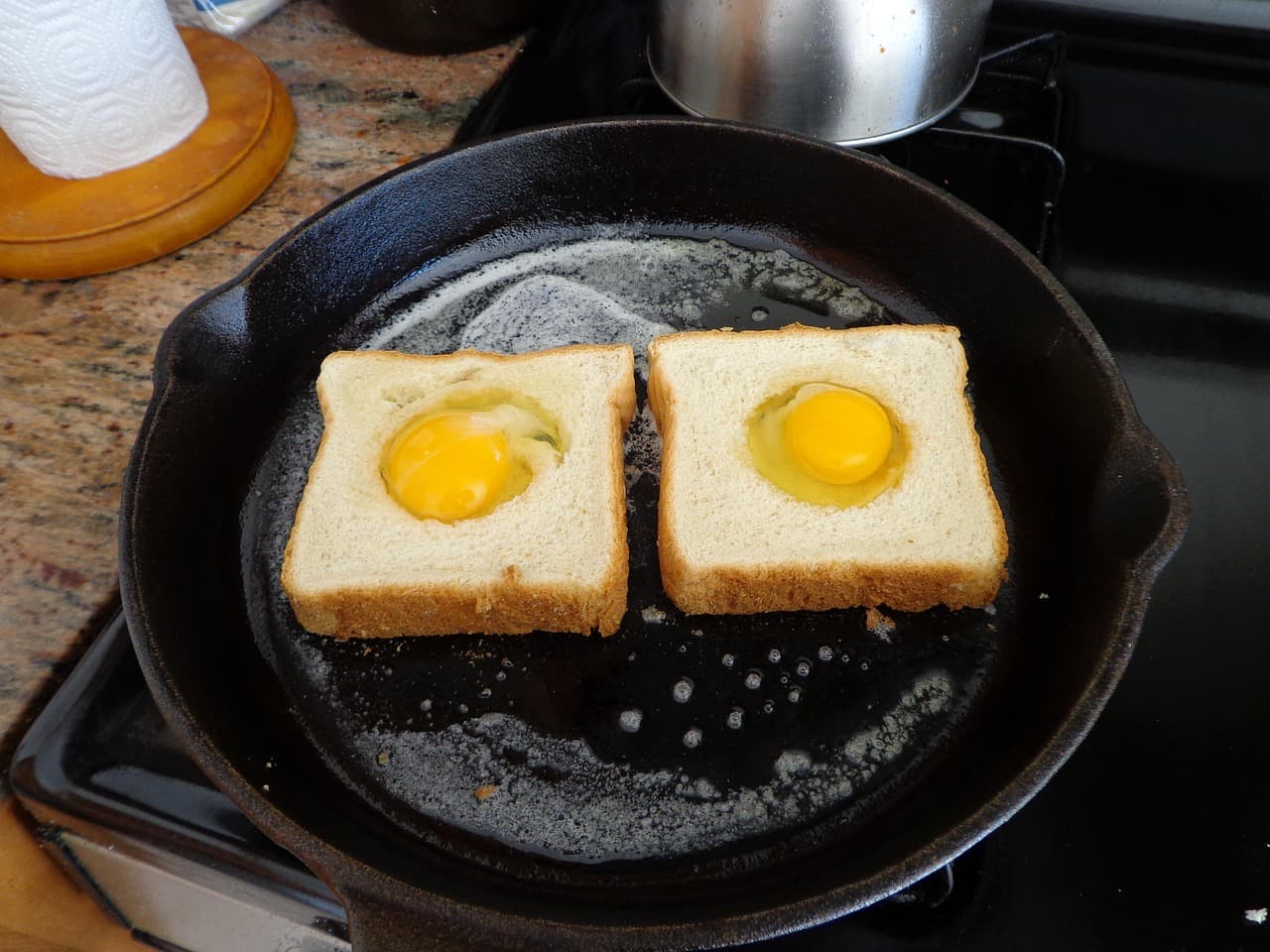 Two eggs fried in the middle of thick toast in a cast-iron pan