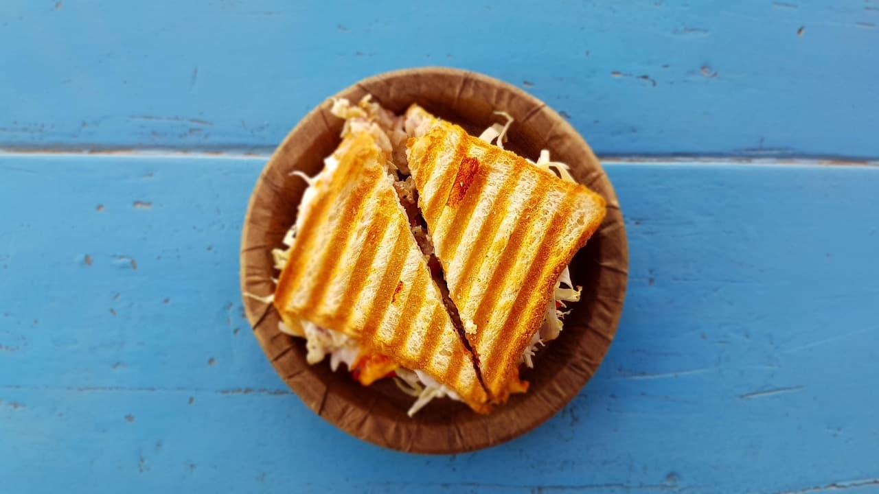 A toasted cheese sandwich cut in half in a wooden bowl