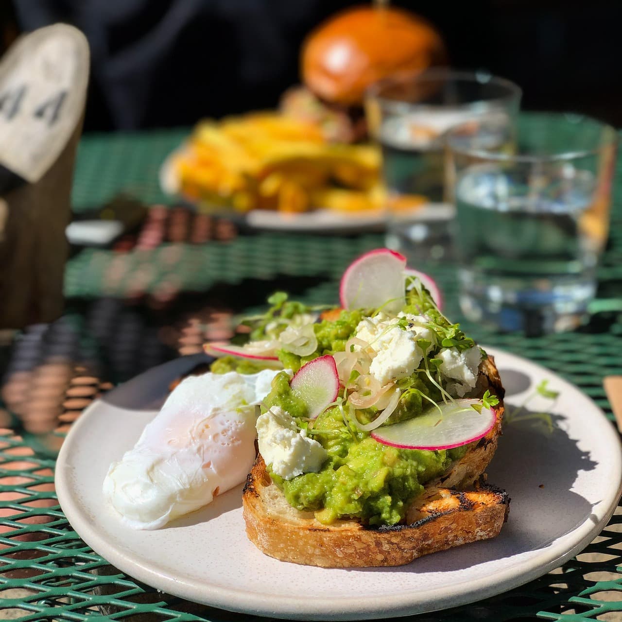 Smashed avocado on toast with a poached egg, radish and feta