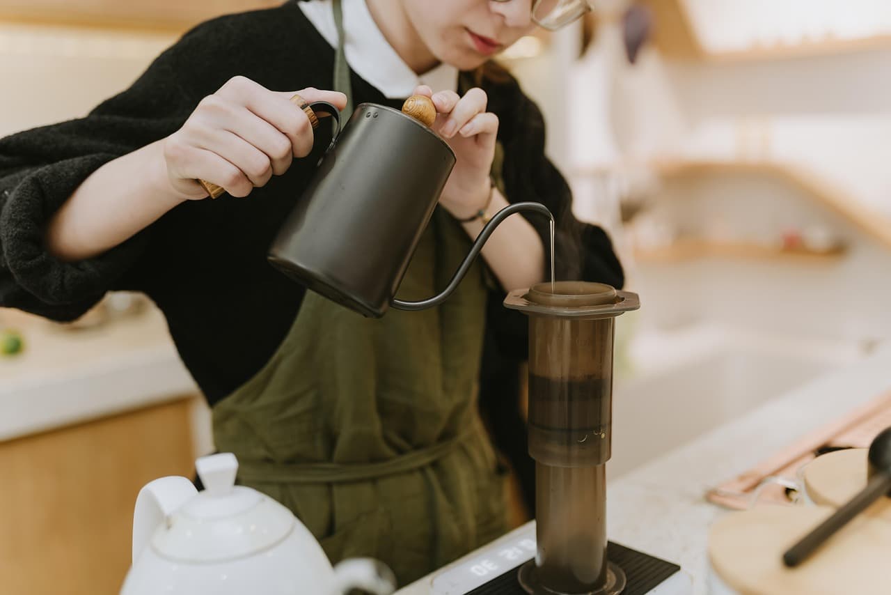 A barista in an apron pouring a filter coffee